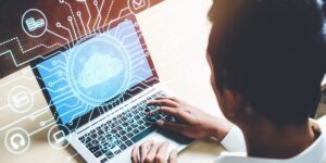 Homem utilizando notebook com ícone de nuvem e linhas que se complementam